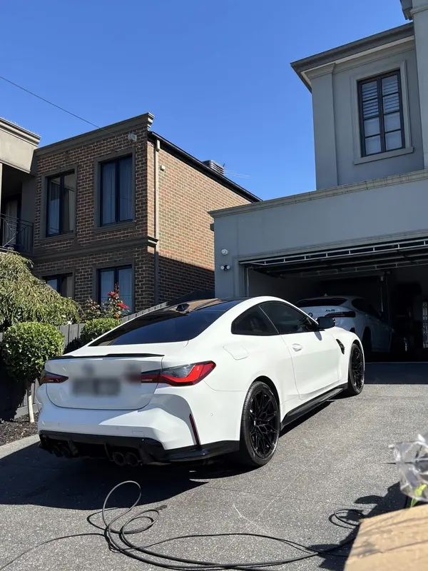White BMW M4 on a driveway, rear three-quarter view