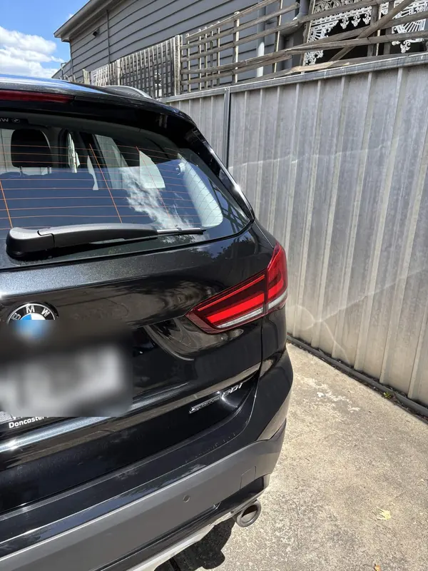 Rear of a black BMW X1 beside a metal fence
