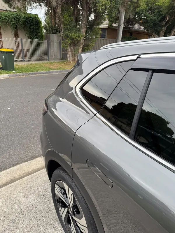 Rear quarter and window line of the Geely EX5 reflecting trees and power lines