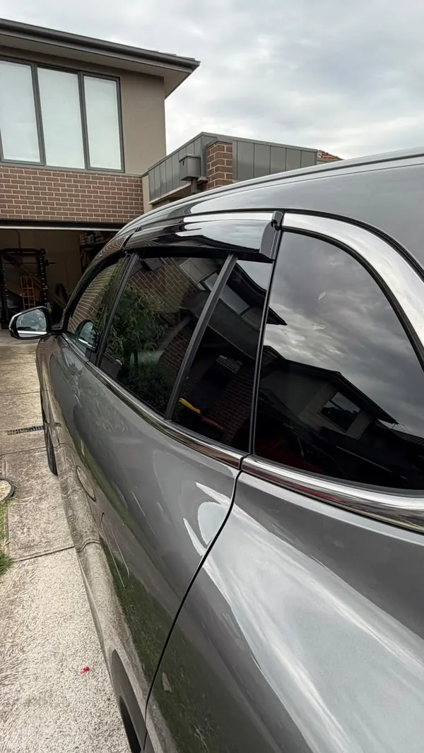 Side windows and door of the Geely EX5 reflecting the neighbouring house