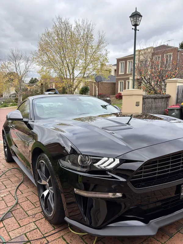 Black Ford Mustang on a brick driveway, front three-quarter view