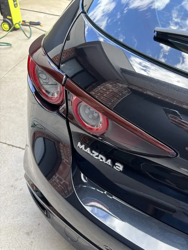 Rear of a black Mazda 3 hatch with the badge in focus