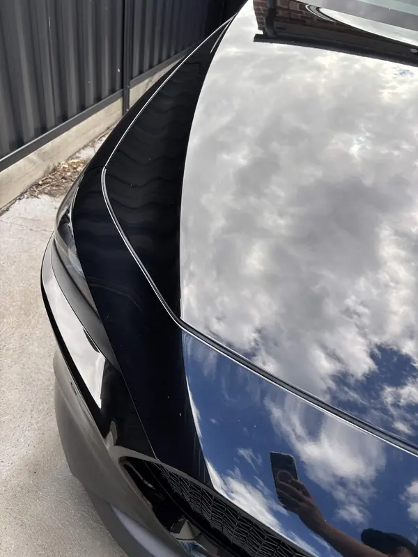 Bonnet of the black Mazda 3 reflecting clouds