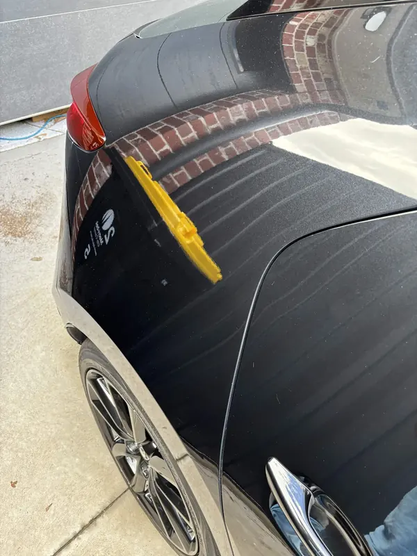 Rear door of the black Mazda 3 reflecting brickwork