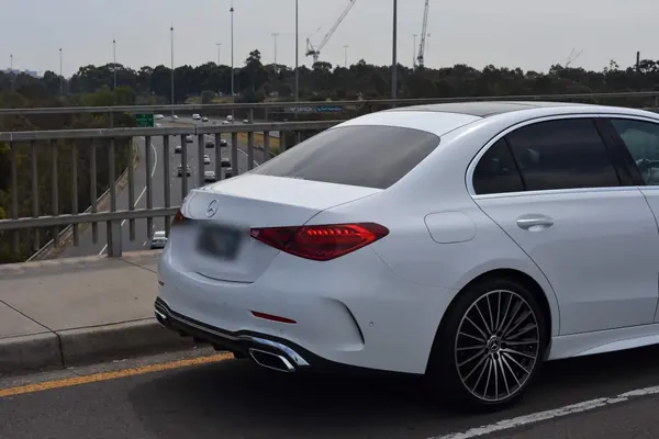 White Mercedes-Benz C-Class by a bridge railing, rear three-quarter view