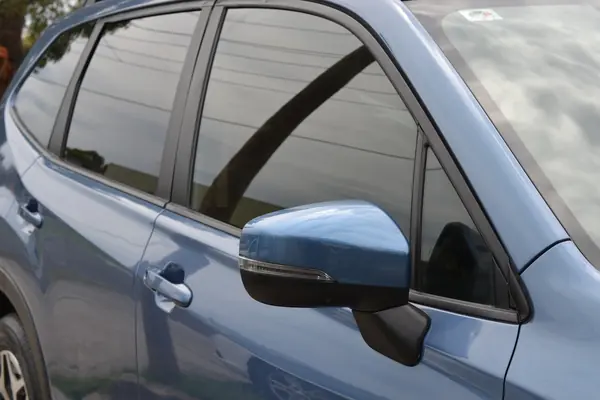Door and mirror of the blue Forester reflecting clouds
