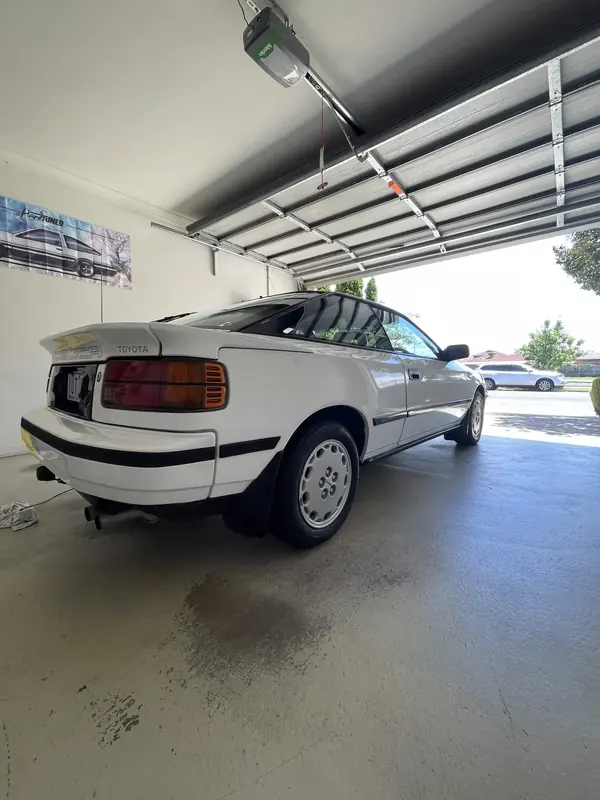 White Toyota Celica in a garage, rear three-quarter view
