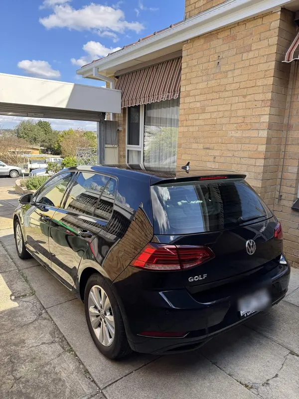 Black Volkswagen Golf on a driveway, rear three-quarter view