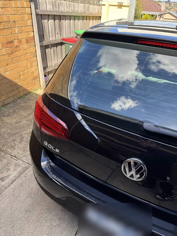 Rear hatch of the black Golf reflecting clouds