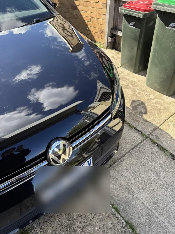 Bonnet of the black Golf with clouds reflected in the paint